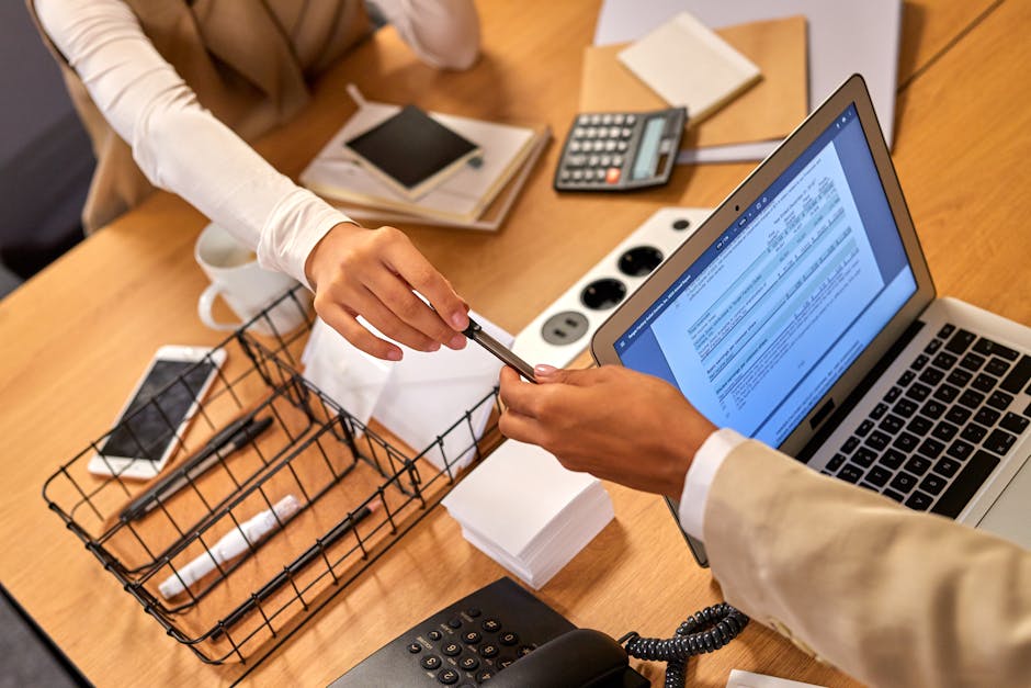 Two professionals collaborating over documents in an office setting, exchanging a pen.